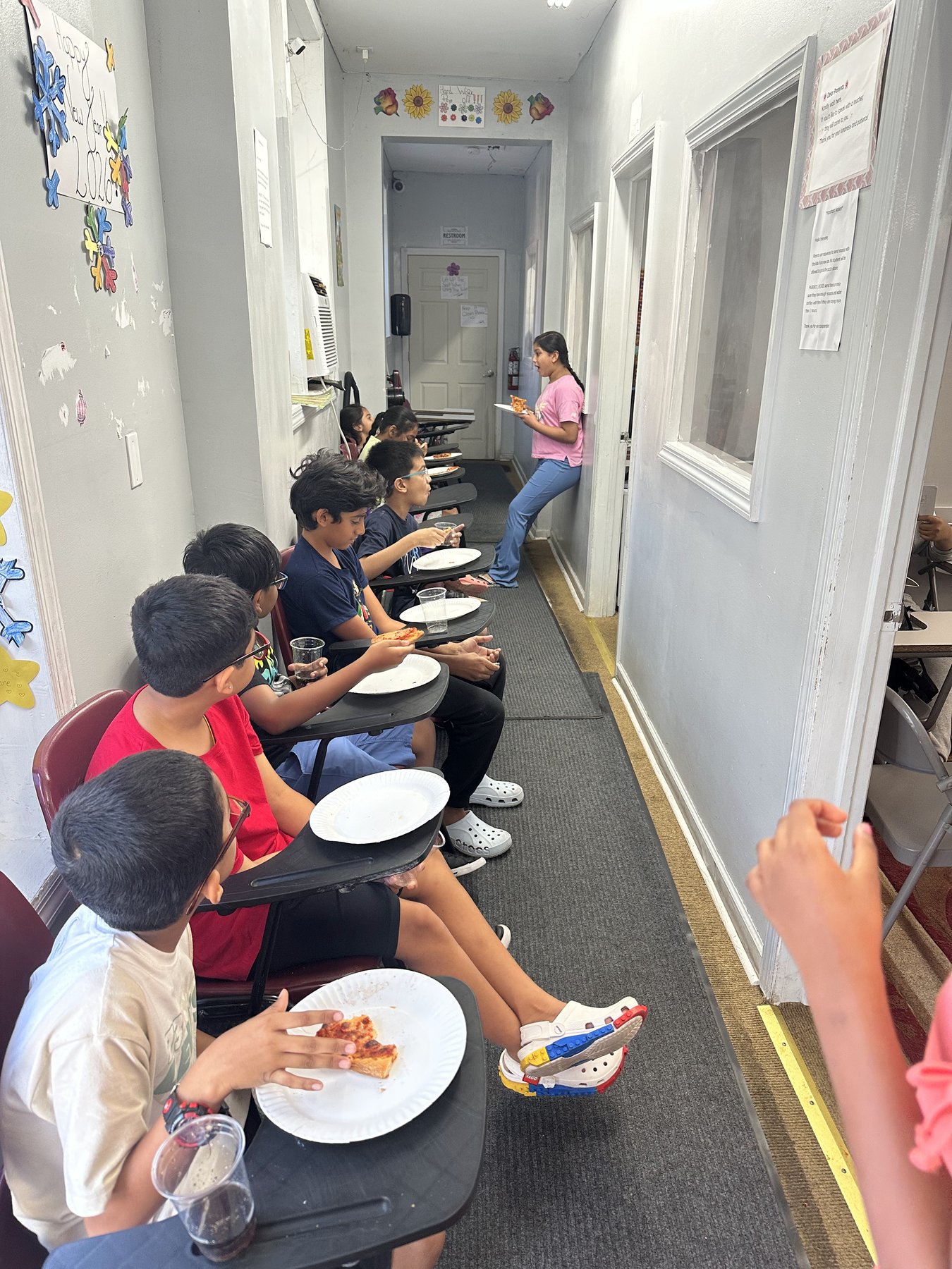 Students sharing pizza together in the hallway at SNR Tutors